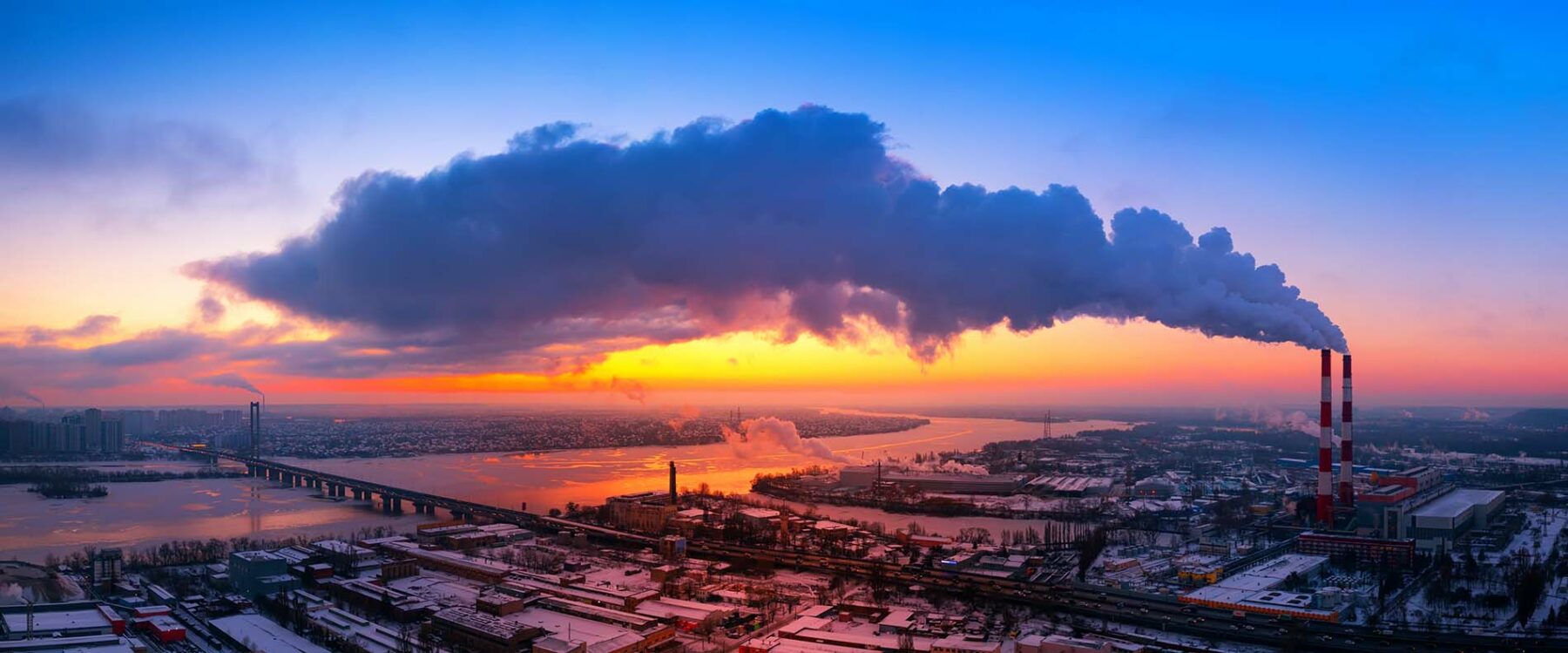 A smoking chimney in an industrial area at sunset